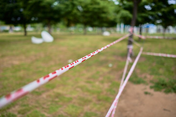 Caution tape with blurred green grass and trees in the background