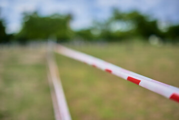 Caution tape with blurred green grass and trees in the background