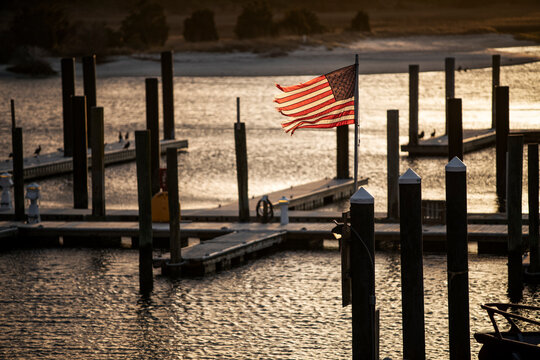A tattered American flag blows in the wind attached to boat dock