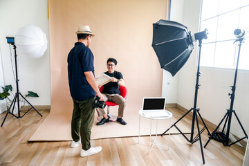 Photographer And Model Prepare For A Photoshoot, Reviewing Props Under Studio Lights