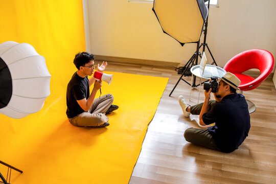 Photographer Captures Seated Man Holding Megaphone In Yellow Studio Setup