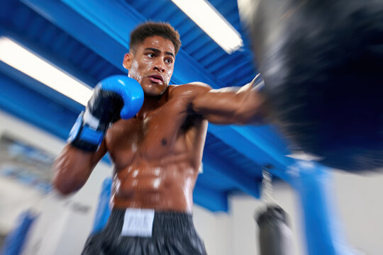 Boxer fighter young man training with punching bag in gym, intense workout and focused expression showing strength and determination