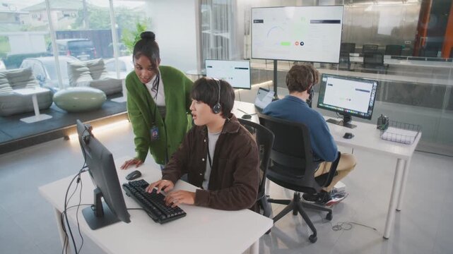 Friendly call center manager providing helpful training to customer support representative as their collaborative team works together in modern office for top service