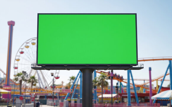 Billboard With Green Screen In Amusement Park, Colorful Rides In Background, Sunny Day
