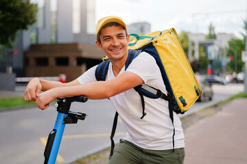 
Delivery man with a backpack on an electric scooter, smiling and looking at the camera. He is...