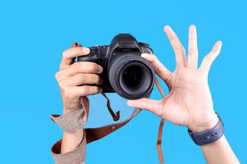 Hands Holding Camera With Strap Isolated On Bright Blue Background