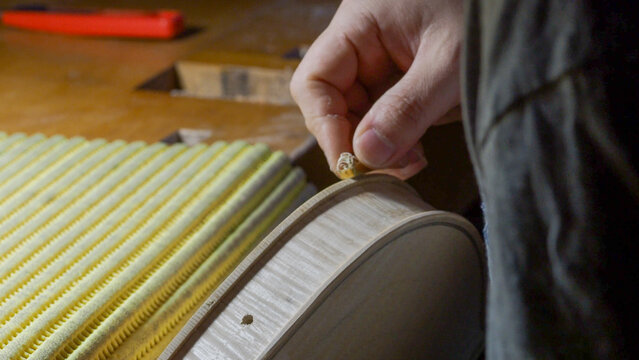 Expert craftsman carefully sanding wooden violin body, highlighting meticulous woodworking techniques in traditional instrument making process