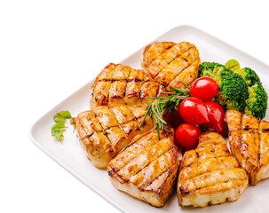 Grilled fish fillets served with fresh vegetables on white plate
