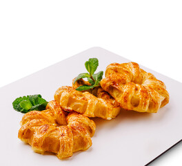 Croissant pastries with spices and mint leaves on a white plate