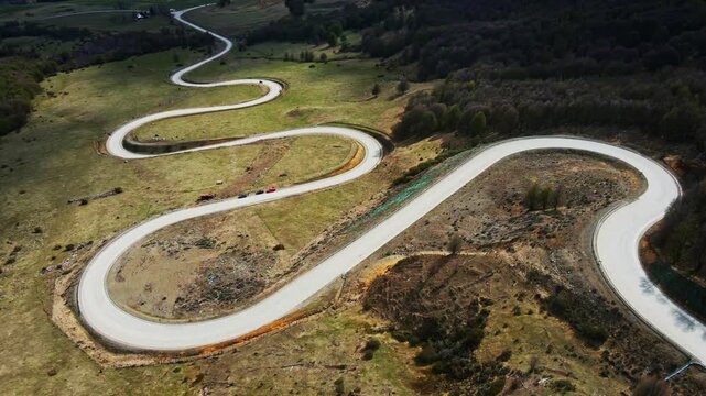 Aerial footage of winding road snakes through lush green fields and forest in Patagonia, Chile