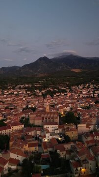 Aerial view of the roofs of Prades with the mountains in the background creating a striking contrast, Prades, Occitanie, France.