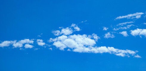Sky is blue and clear with clouds. The sky is very bright. Scattered white clouds creating a serene...