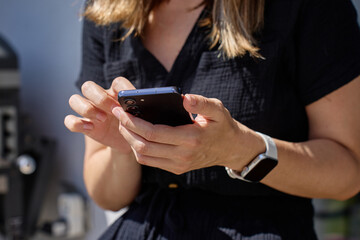 Woman using smartphone. Close-up of female hand holding modern mobile phone outdoors in daylight....