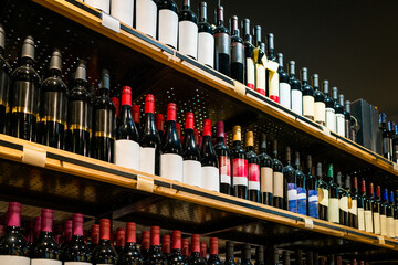 Low-angle view of wine bottles on shelves in liquor store