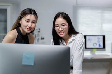 Two businesswomen working together on desktop computer in modern office