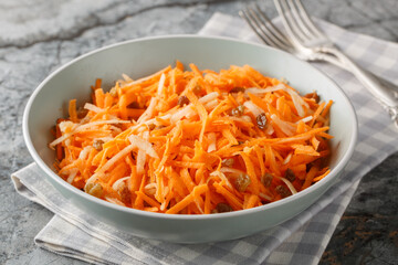 Juicy carrot apple salad with raisins with lemon dressing close-up in a bowl on the table. horizontal