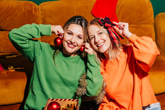 Two friends celebrating Christmas with gifts in a cozy living room