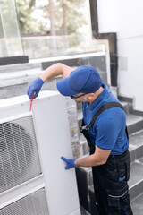 Repairman fixing AC outdoor unit.