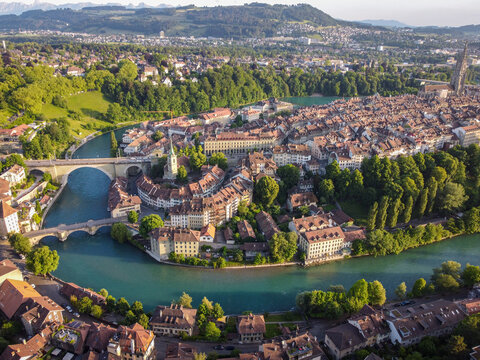 Aerial view of the Aare River curving around the old city with its distinctive red-tiled roofs and the towering Bern Minster, Bern, Canton of Bern, Switzerland.