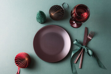 Christmas table setting with plate, wine glass, festive decorations and cutlery tied with ribbon on...