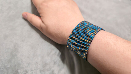 Turquoise bracelet with gold plated beads on the hand and light background.