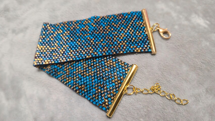 Turquoise bracelet with gold plated beads on the hand and light background.