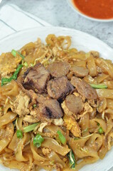 Char Kway Teow, fried rice flat noodles with beef, egg, and vegetables on a white plate, Indonesian...