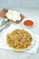 Char Kway Teow, fried rice flat noodles with chicken, Egg, and vegetables on a white plate,...