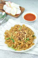 Char Kway Teow, fried rice flat noodles with chicken, Egg, and vegetables on a white plate,...