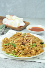 Char Kway Teow, fried rice flat noodles with chicken, Egg, and vegetables on a white plate,...