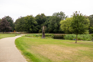 Scenic park view with a winding pathway, pond, green trees, and open grassy areas