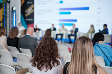 Participants sit attentively at a panel discussion during a professional conference showcasing insights.