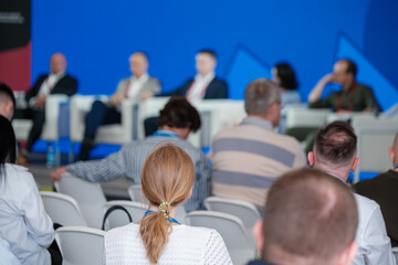 Professional audience attending business conference focusing on a panel discussion and presentation.