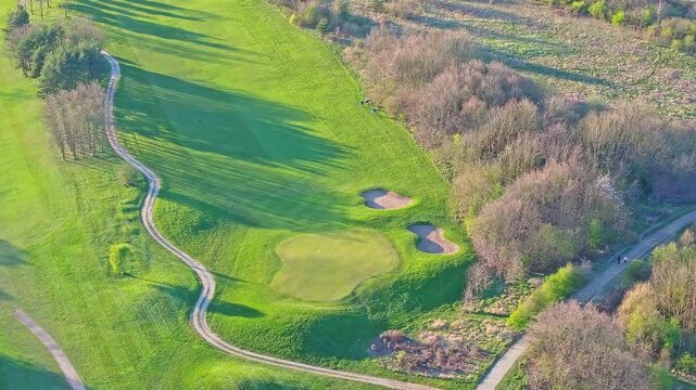 Aerial view of golfers walking down the fairway at Waterfront Golf Club, Rotherham, South Yorkshire, UK, on a sunny autumn morning.