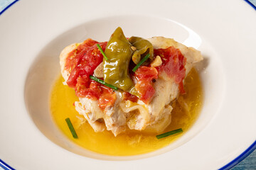 Steamed sea bass in a white porcelain plate on a blue stone table