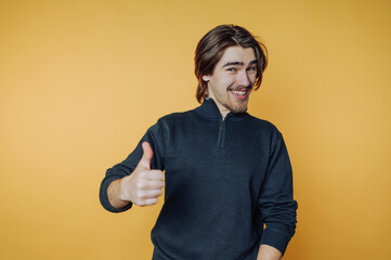 portrait of young man gives a thumbs up with a wide smile, conveying happiness and approval on...
