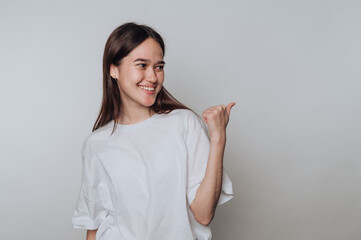 portrait of young joyful woman making a playful gesture while sporting a casual white shirt on...