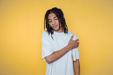 portrait of young man with stylish dreadlocks poses pensively, reflecting a calm mood on yellow...