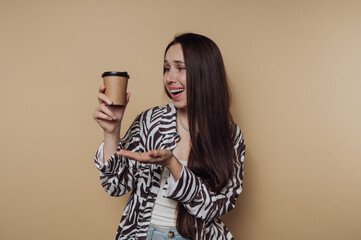portrait of young excited woman joyfully holds a coffee cup, showcasing her happy expression on...