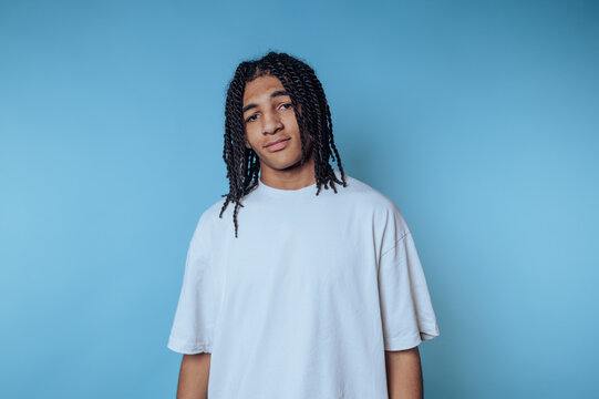 portrait of young man poses pensively, showcasing a mix of confidence on blue background