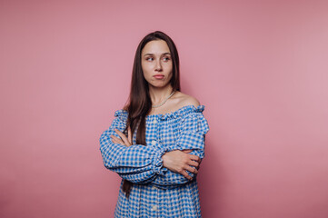 portrait of young thoughtful woman crosses her arms, displaying an expression of contemplation on...