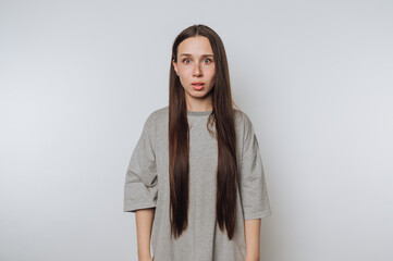 portrait of young young woman wears a surprised expression while standing still on light background