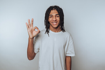 portrait of young man with dreadlocks smiles and gives an okay sign, showcasing positivity and joy...