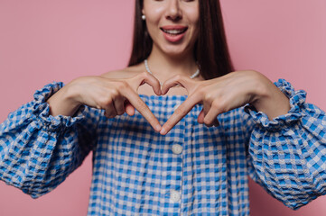 portrait of young woman showcasing a heart gesture with her hands, embodying love and joy with a...