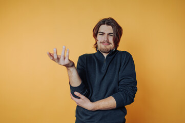 portrait of young man looks puzzled, gesturing with one hand up as if questioning something on...