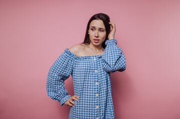 portrait of young woman appears uncertain, slightly frowning on pink background
