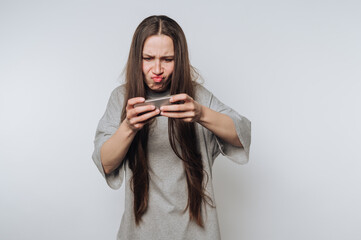 portrait of young woman is intensely focused on her mobile game, displaying frustration on light...