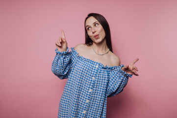 portrait of young woman joyfully poses in a blue gingham top, playfully showcasing her charisma on...