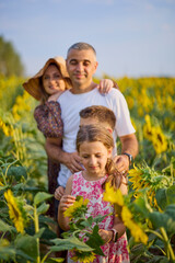A beautiful family on a farm enjoys a sunflower field together