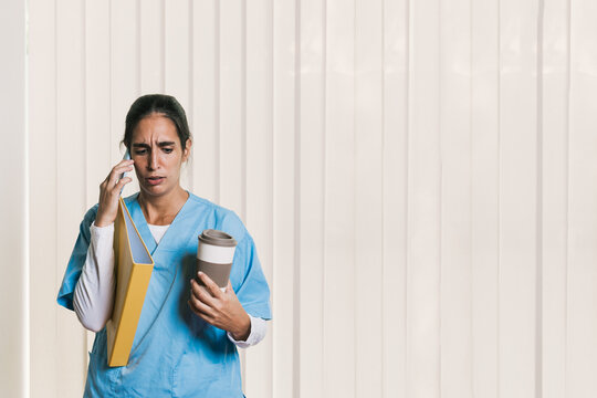 Physiotherapist holding coffee and folder while calling patient - Powered by Adobe